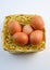 five red chicken eggs inside a basket on white background