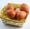 five red chicken eggs inside a basket on white background