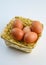 five red chicken eggs inside a basket on white background