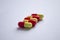 Five red and yellow capsules on a light background