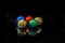 Five round balls of chocolate candies in a multi-colored wrapper foil are isolated on a black background. Studio, defocused ob