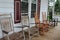 Five rustic rocking chairs on wood porch of country home invite guests to sit and chat for a bit