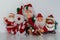 Five Santa ornaments with four standing and one seated, waving at the camera.