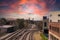 Five sets of railroad tracks near a red brick building with graffiti with railroad traffic signals