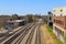 Five sets of railroad tracks near a red brick building with graffiti with railroad traffic signals