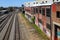 Five sets of railroad tracks near a red brick building with graffiti with railroad traffic signals