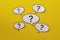 Five speech bubbles with question marks over a bright yellow background