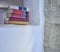 Five stacked books placed inside a high space in wall book titles right angle indoor open space white wall studio rustic stone