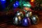 Five sweets in multi-colored foil lie on a wooden surface. Near the Christmas tree and multi-colored LED lights. Night magic.