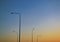 Five tall lampposts against a gradient evening clear sky at sunset