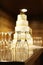 Five tiered wedding cake with empty champagne flutes on table