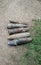 Five unexploded artillery shells lie on the side of the asphalt road, dandelions bloom and the grass turns green