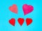 five various hearts cut from red papers on blue