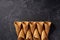 Five waffle cones waiting to be filled with ice crea, on dark background, top view