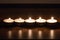 Five wax candles in one line burning on wooden table