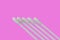 Five white cotton buds with plastic material isolated on a pink background