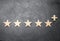 Five wooden stars and a plus, on a concrete gray background. The concept of the highest evaluation of quality and service.