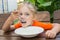 Five-year girl with pleasure eats porridge for breakfast