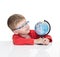 The five-year-old boy in blue points sits at a white table and holds the globe in hand