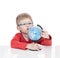 The five-year-old boy in blue points sits at a white table and holds the globe in hand