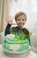 Five-year-old boy on his birthday with a beautiful festive cake in green tones