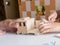 A five-year-old boy independently assembles a wooden construction kit with a screwdriver. Hands close-up.