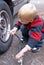 Five year old child filling a car tire with air.