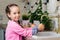 A five-year-old girl in a pink coat wants to help her parents wash apples in a vintage kitchen. Retro interior. Portrait