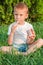 A five-year-old red-haired boy sits in a park and eats ice cream. The child eats ice cream in nature