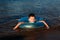 Five-year-old smiling child swims in the sea