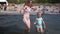 Five years old blond girl with swimsuit having fun water waves with woman mother