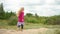 Five years old blonde girl with pink shirt walking barefoot on top of dune sand