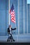 A five years old smiling boy is sitting on a bicycle and holding american flag on a stick