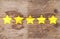 Five yellow ranking stars on wooden background