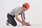Fixing the floor. Man in casual clothes and orange colored hard hat have some work using hammer. White background