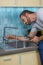 Fixing leaky faucet. Professional plumber looking concentrated, using pipe wrench while examining and fixing faucet in