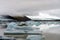 Fjallsarlon glacier lagoon at the end of Vatnajokull glacier. Green moss and volcanic ash in the background.