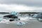 Fjallsarlon glacier lagoon at the end of Vatnajokull glacier. Green moss and volcanic ash in the background