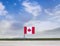 Flag of Canada with vast meadow and blue sky behind it.