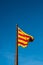 Flag of Catalonia. Senyera. Red and yellow striped flag and on clean blue sky background. Flag waving in the wind in sunny day