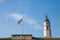 Flag with the coat of arms of belgrade next to Clock tower of Kalemegdan, also known as Sahat Kula, during a sunny afternoon.