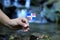 Flag of Dominican Republic in water environment. Hand of young man holds this state symbol near waterfall and river. Concept of