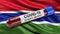 Flag of Gambia waving in the wind with a positive Covid-19 blood test tube. 3D illustration concept.