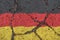 Flag of Germany on the cracked asphalt. The concept of crisis, default, pandemic, conflict, terrorism. Out of focus image