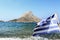 Flag of Greece waving at Telendos island and blue sea background