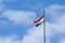 Flag of Hungary also called magyarorszag zaszlaja waiving on a flagpole of Budapest, in front of a blue sunny sky.