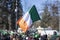 Flag of Ireland close-up in hands on background of blue sky during the celebration of St. Patrick`s Day