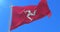 Flag of the Isle of Man waving at wind in slow in blue sky, loop