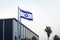 flag of Israel flutters in the wind against the background of the business state building. View of the Israeli flag in the streets