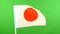 Flag of Japan on flagpole on green background. Japanese Flag waving in wind.